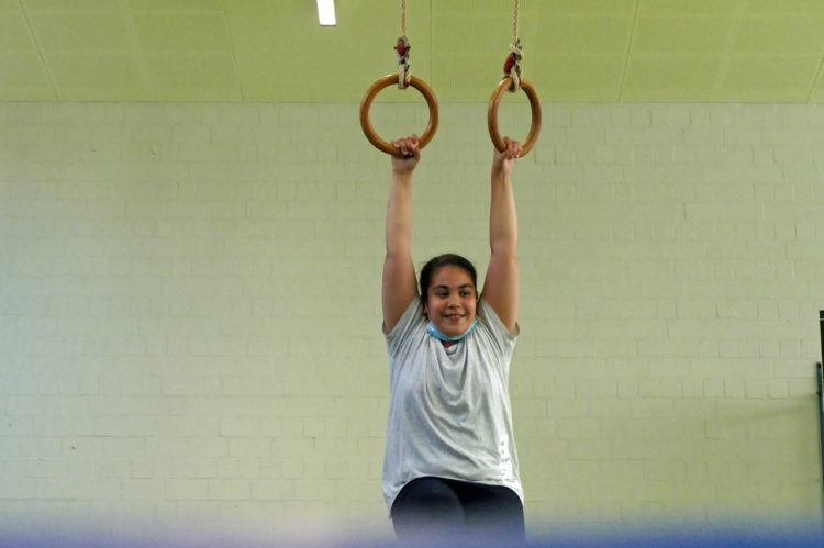 Ein Mädchen macht Sport in der Halle an Ringen