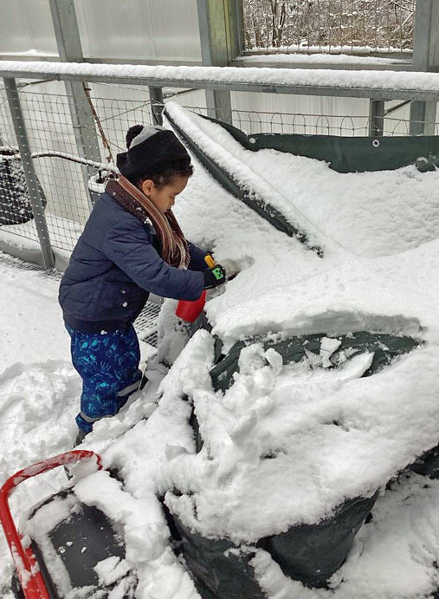 ein kind befreit spielfahrzeuge von schnee