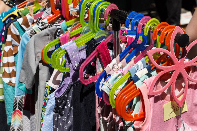 kleiderstange-mit-bunten-kleiderbuegeln-und-kinderbekleidung